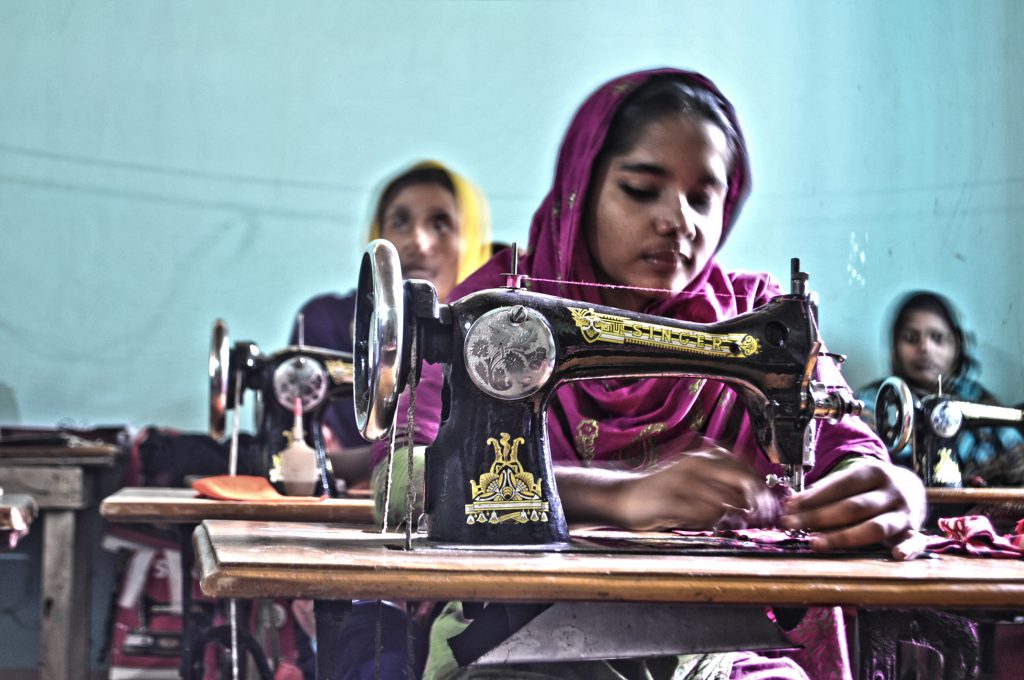 A Young Girl Sews Fabric for a Clothes Retailer