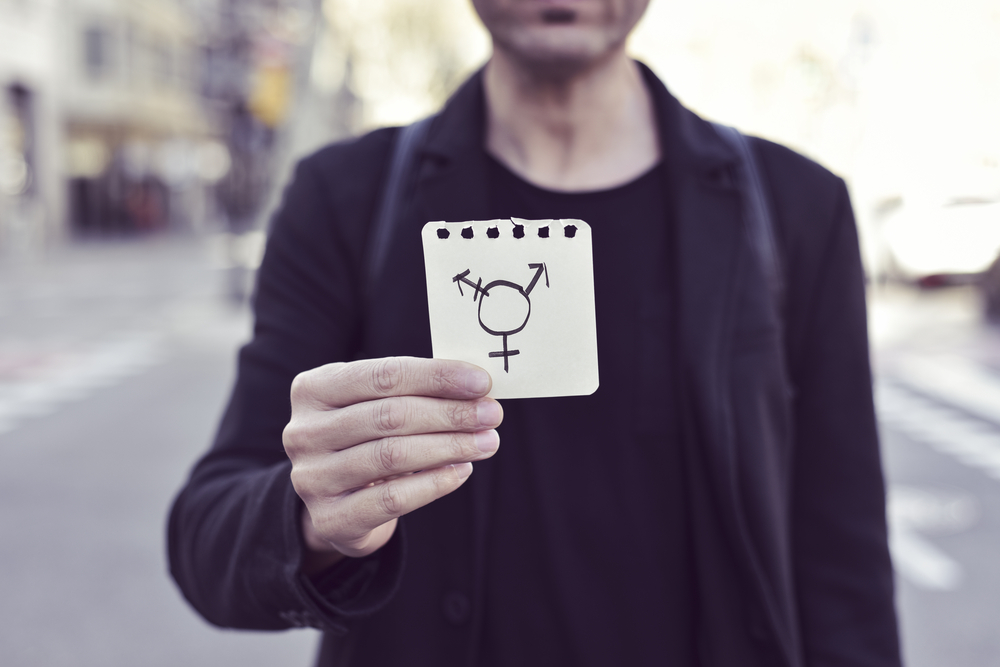 Young man holding up transgender symbol