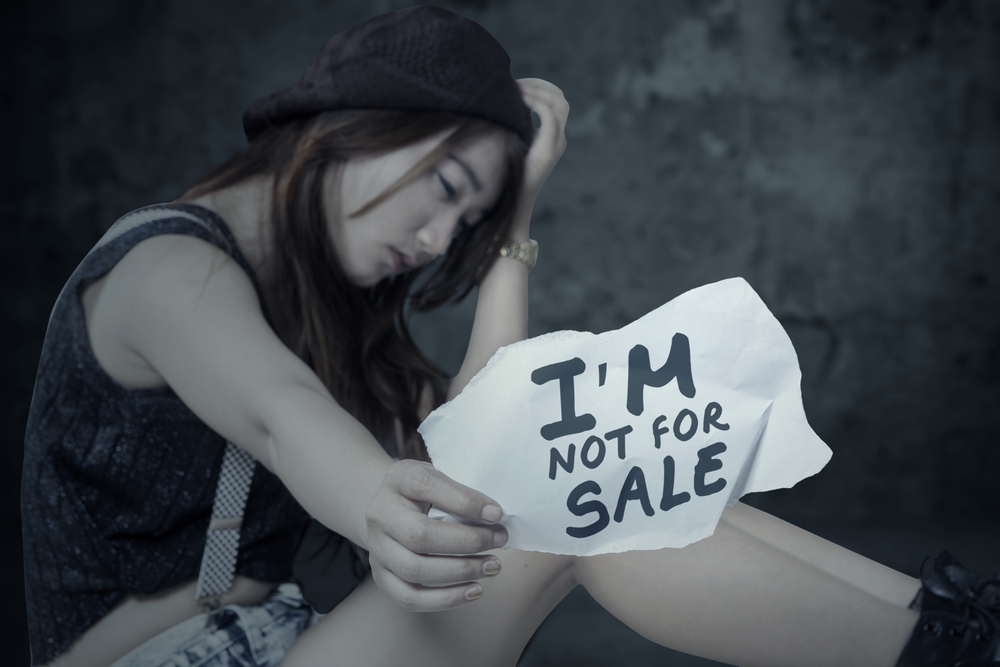 Human trafficking victim with a sign saying she's not for sale